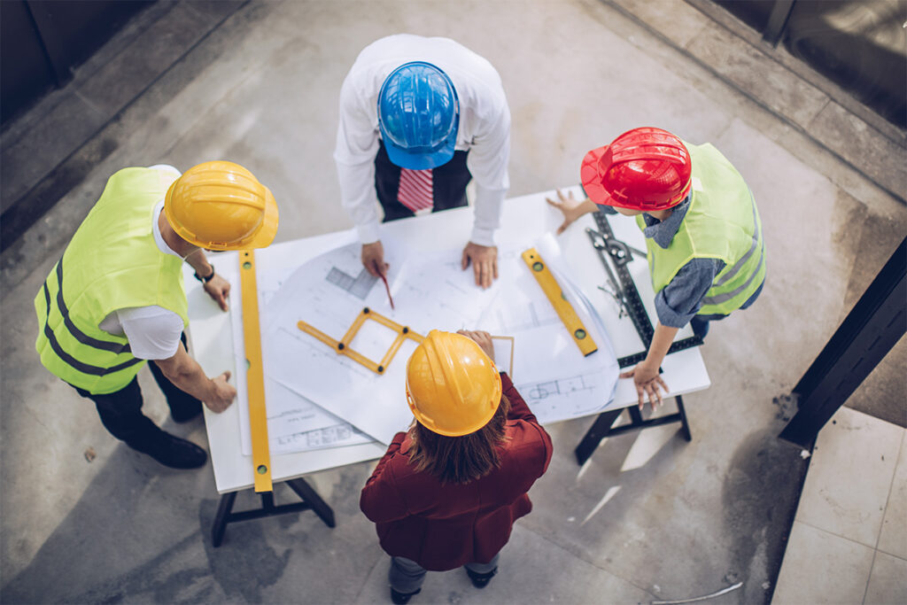 Four people looking at blueprints on a construction site