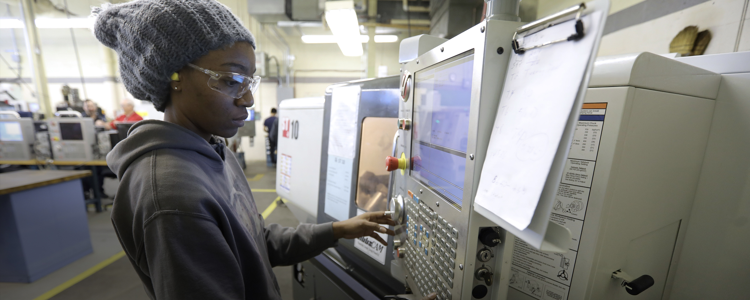 Student working on CNC machine in a shop