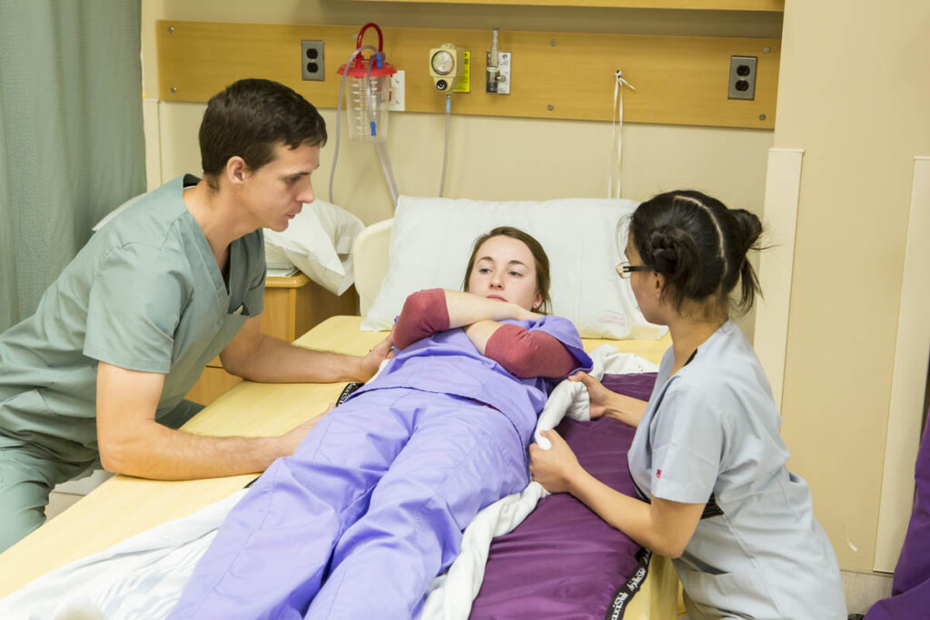 Health care aides examining patient in hospital bed