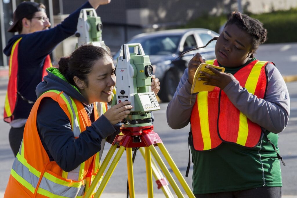 Students outside learning how to use surveying equipment