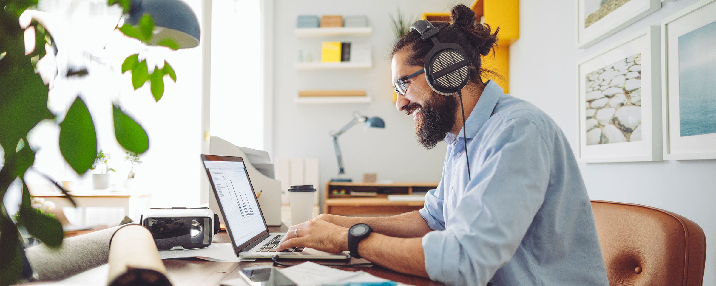 Man wearing headphones and working on laptop in modern home office