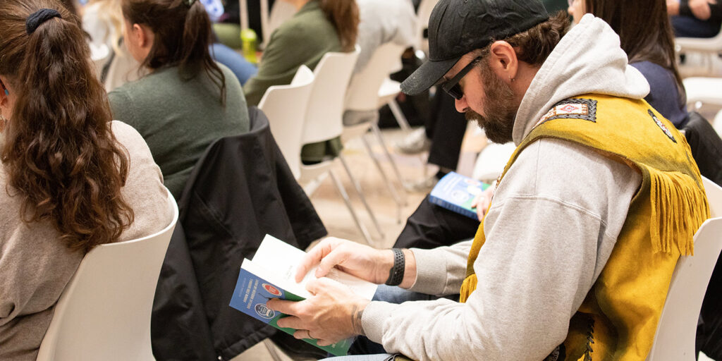 People in a seminar reading from a book